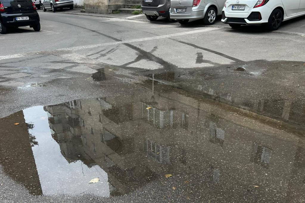 În spatele blocurilor de pe Strada Mihai Eminescu, din Câmpina, curge apa pe carosabil din... aprilie!