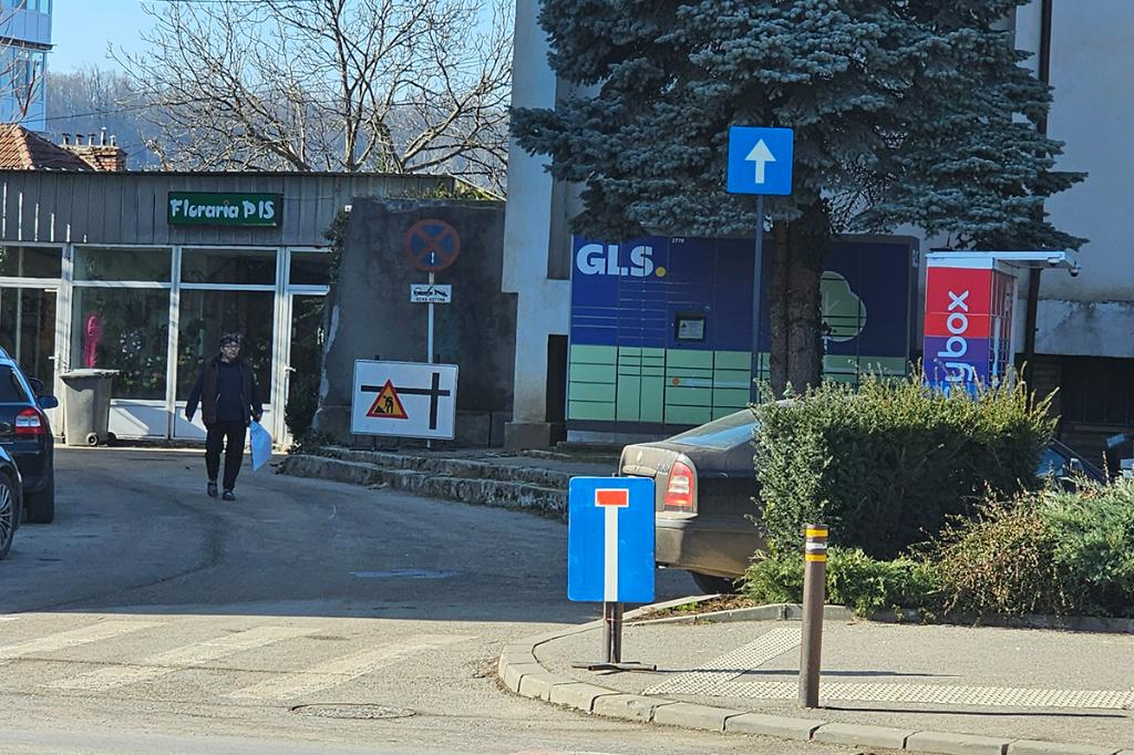 Indicator rutier aproape de nivelul solului, pe un stâlp pietonal de pe trotuar